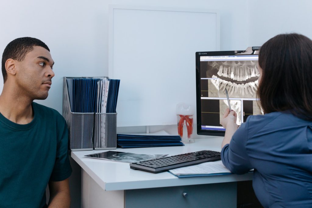 Dentist reviewing a panoramic dental x-ray on screen with a patient
